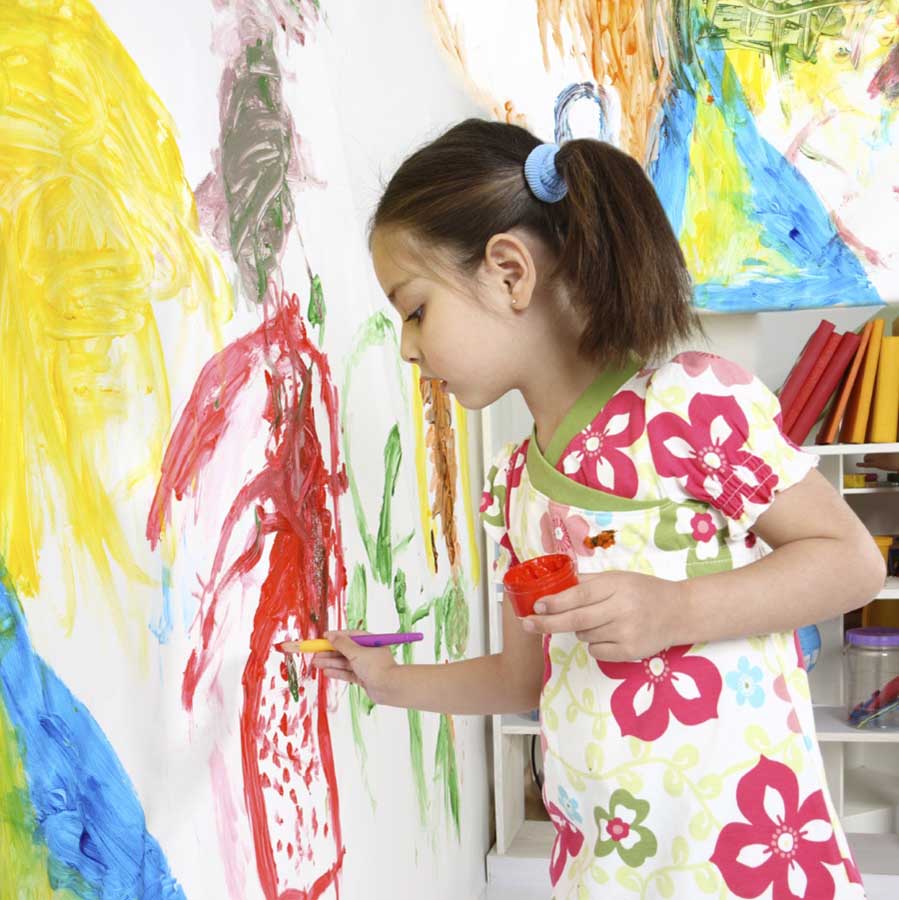 Lapsi maalaa seinällä olevalle paperille.