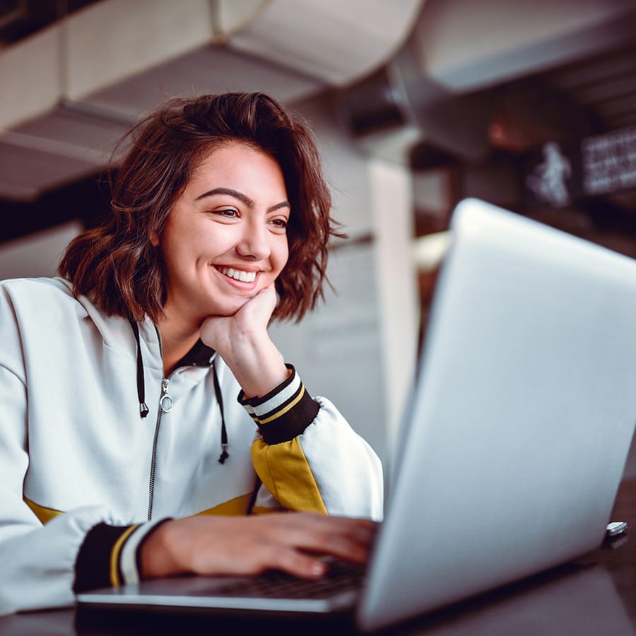 "Hymyilevä nainen työskentelee kannettavalla tietokoneella."